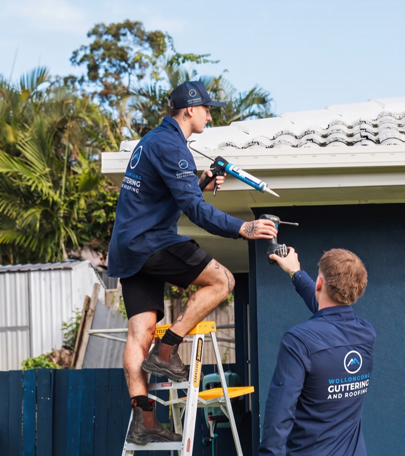 Roofing team repairing part of a gutter at a customer's home
