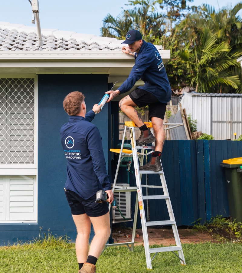 Roof plumbers working together to repair a damaged roof